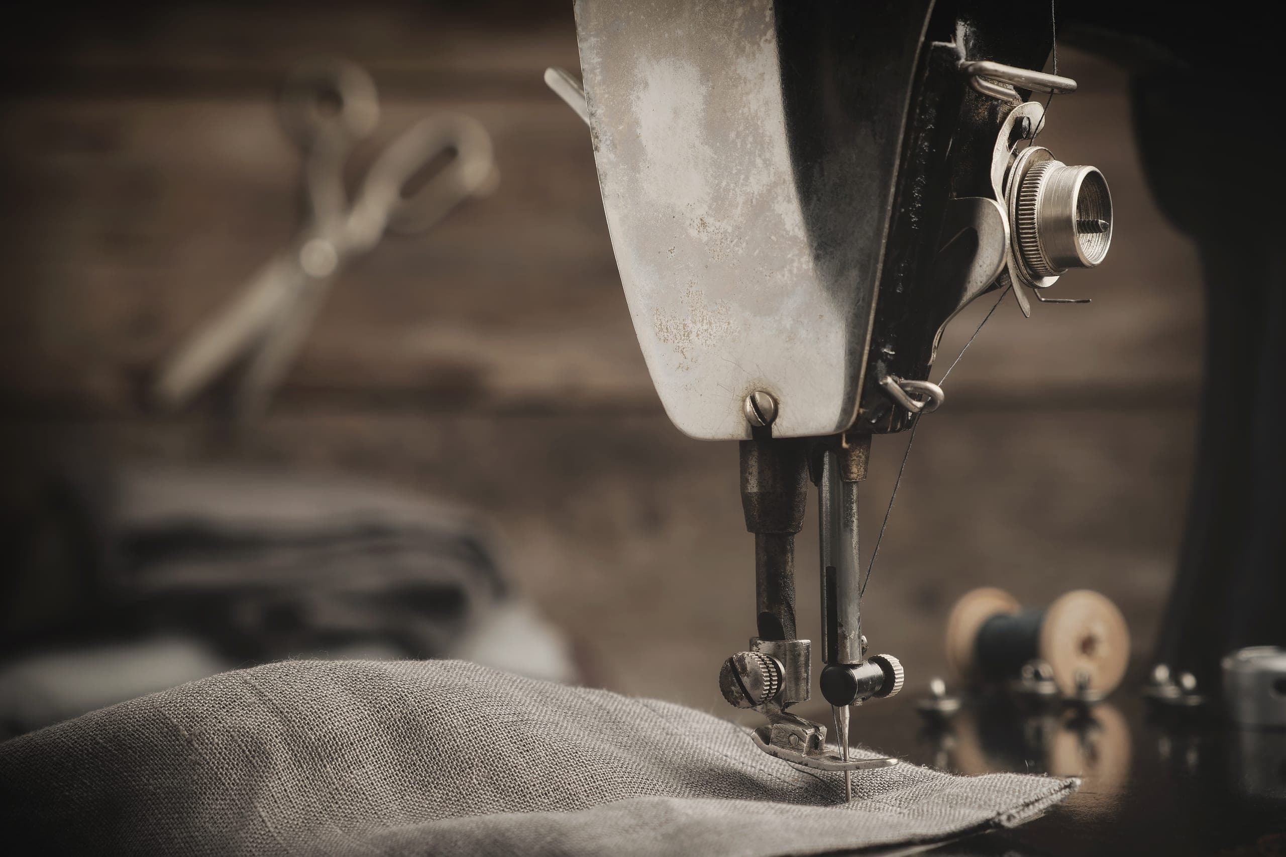 An old sewing machine stitching linen, tailoring shears behind it