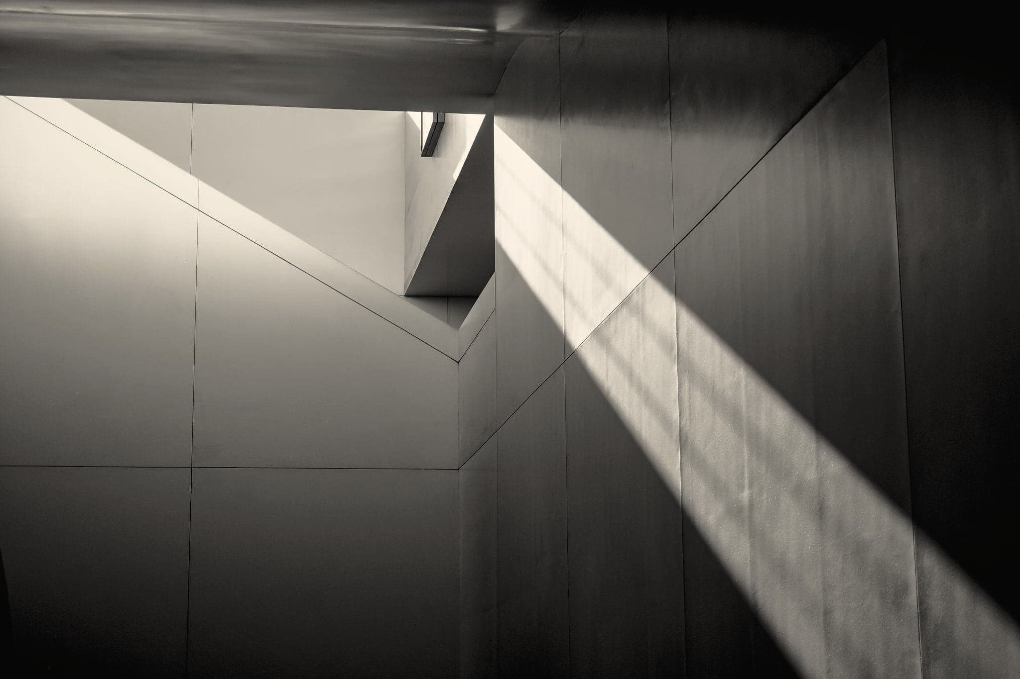 A beam of light falling across white walls from a skylight